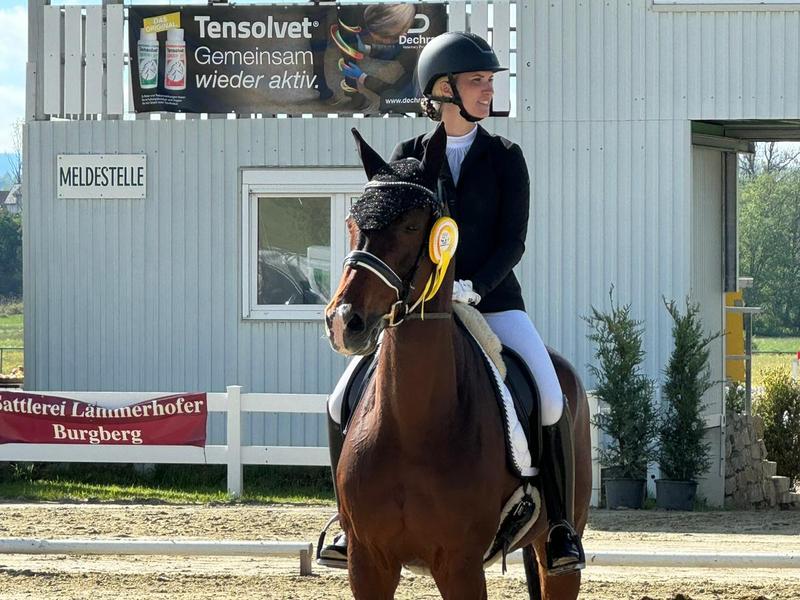 Melanie Müller auf ihrem braunen Pferd mit gelber Turnierschleife nach einer Prüfung