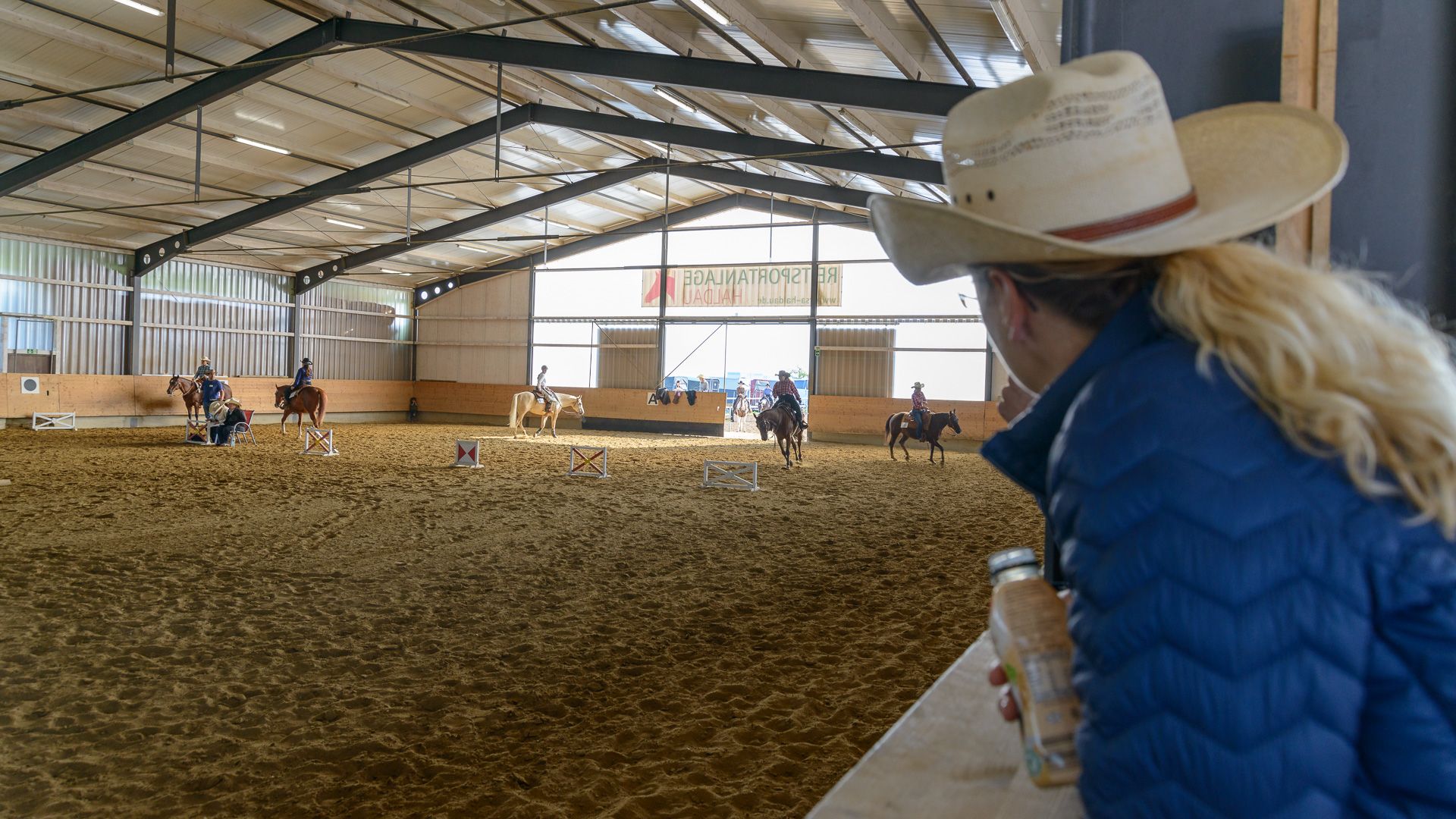 Westernreiter beim Turnier in der Reithalle der Reitsportanlage Haldau, im Vordergrund eine Zuschauerin mit Cowboyhut