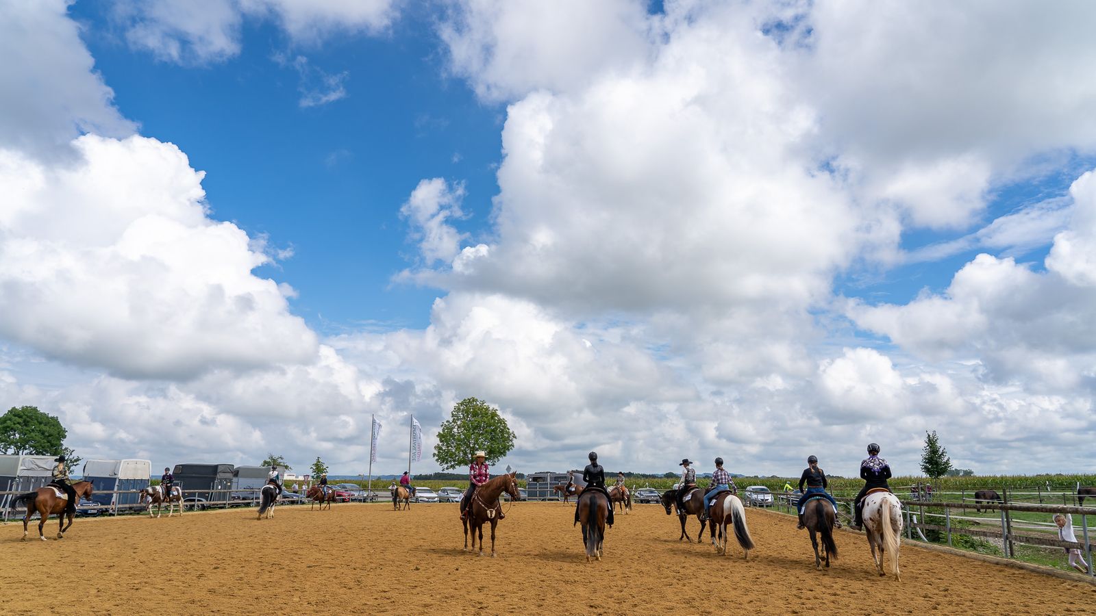 Reiter auf dem Außenreitplatz der Reitsportanlage Haldau, im Hintergrund Pferdeanhänger und Fahnen