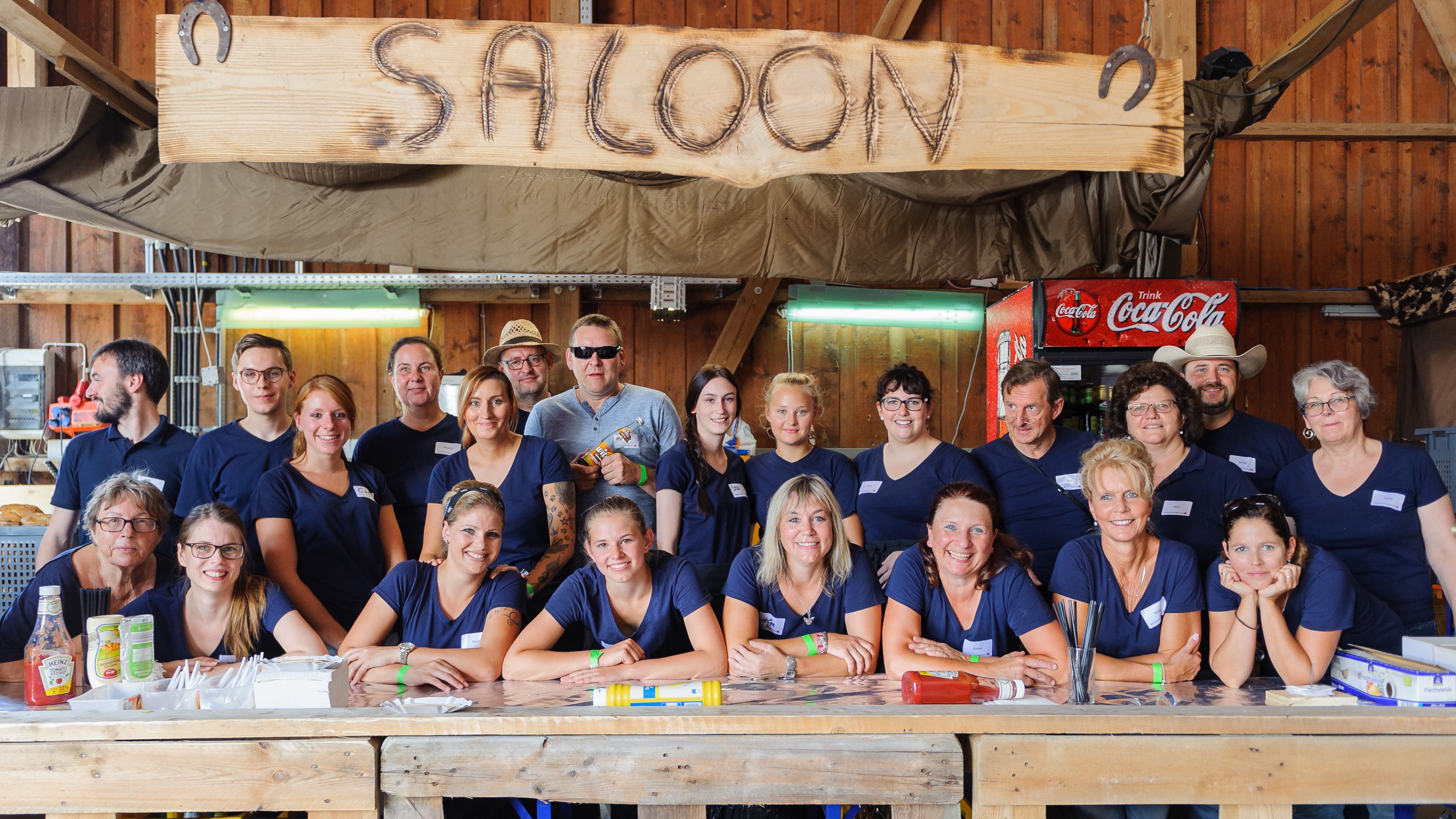 Gruppenbild des Helferteams in dunkelblauen T-Shirts an der Theke