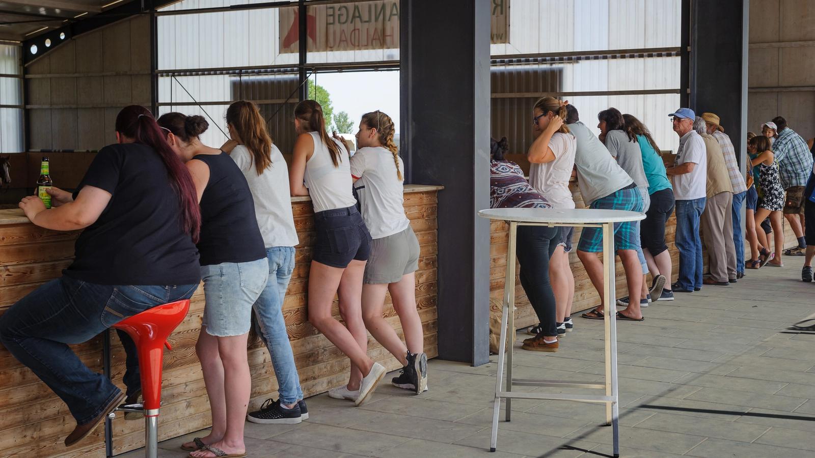 Zuschauer stehen bei einer Veranstaltung an der Holzbande der Reithalle