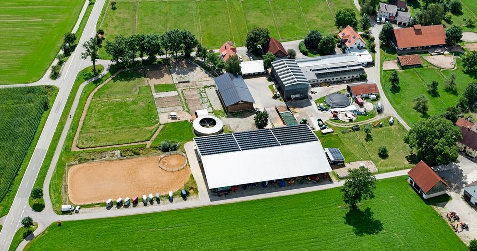 Luftbild der Reitsportanlage Haldau: Reithalle mit Photovoltaik-Dach, Außenplatz, Longierzirkel, Koppeln und Hof