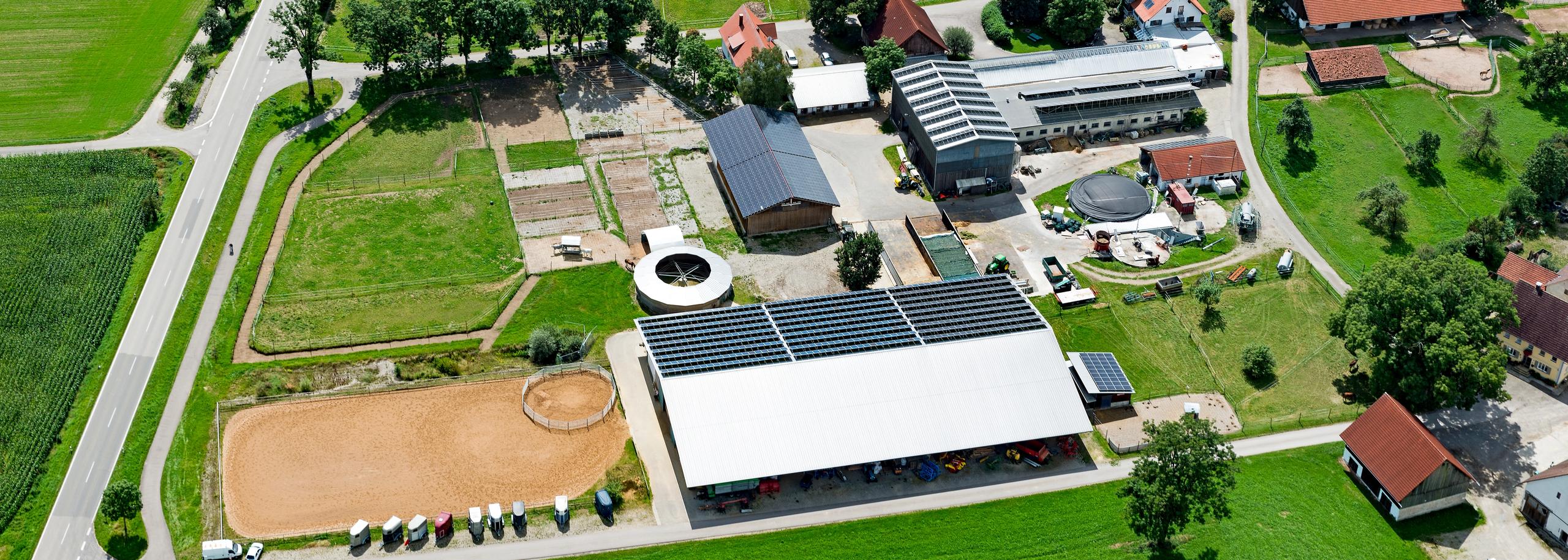 Luftbild der Reitsportanlage Haldau: Reithalle mit Photovoltaik-Dach, Außenplatz, Longierzirkel, Koppeln und Hof